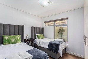 Camera d'albergo con due letti, una finestra vista e un comodino con lampada.