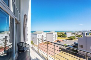 A balcony with a view of a residential area and the sea.