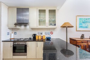 A modern kitchen with a Bosch oven, a gas stove, and a stainless steel range hood. There are cabinets with glass doors and a black countertop.