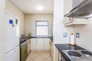 A compact kitchen with a window, a stove, and a refrigerator.