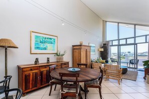 A dining area with a round table, chairs, a cabinet, and a large window offering a view.