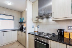 Una cucina moderna con mobili chiari in legno, una cappa aspirante in acciaio inossidabile, un piano cottura a gas e un forno integrato.
