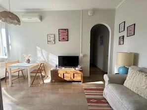 A living room with a TV, wooden furniture, a sofa, and a dining area with a table and chairs.