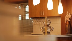 A kitchen with wooden cabinets, pendant lights, and a decorative tea set on the counter.