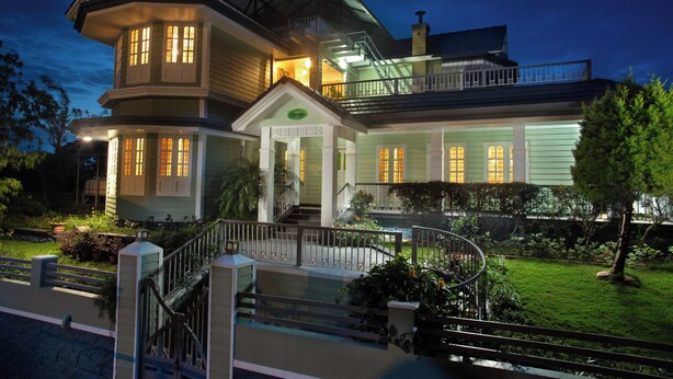 A two-story house with a balcony, a front porch, and a well-maintained garden.