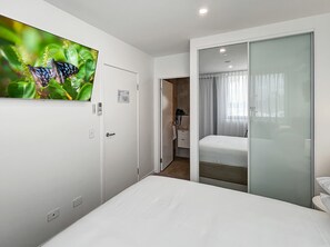 A hotel room with a bed, a bathroom, and a door leading to another room.