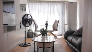 En moderne stue med et rundt sofabord, en ventilator, en sofa og et køleskab.