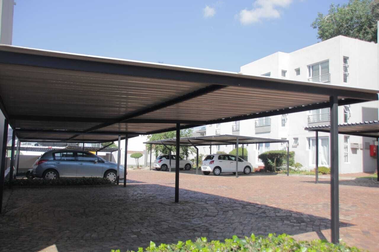 A covered parking area with three cars parked under a metal roof.