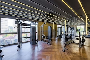A gym with exercise equipment, large windows, and wooden flooring.