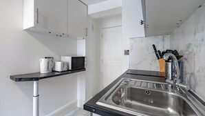 A modern kitchen with a stainless steel sink, a black countertop, and white cabinets.