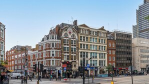 A street view with historic buildings, a modern high-rise, and a busy intersection.