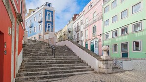 Una scala conduce a edifici colorati, con un sentiero acciottolato che indica “Capela Santo Amaro”.
