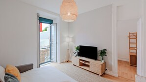 Una camera da letto moderna con un letto, una TV su un mobile in legno, una lampada a sospensione e una porta finestra.