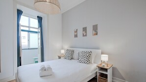 Una camera da letto ordinata con un letto grande, due comodini con lampade e un piccolo contenitore sotto il letto.
