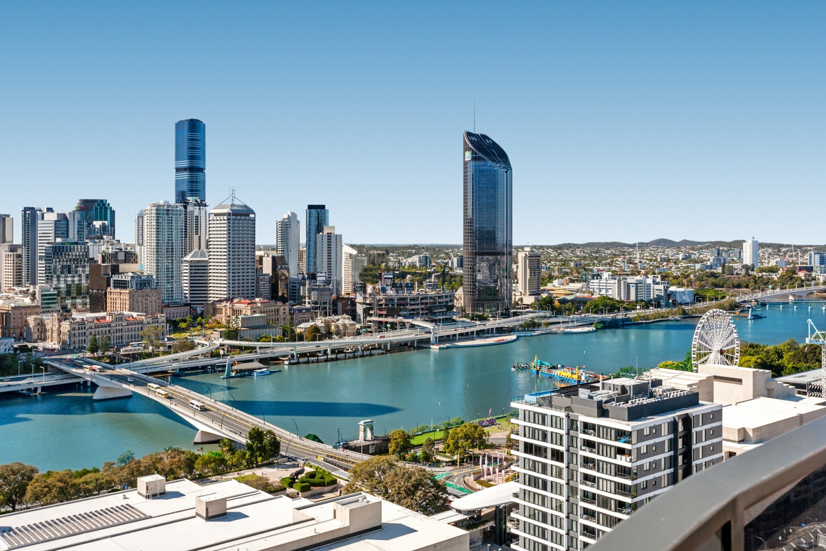 A cityscape with modern skyscrapers, a river, and a bridge.