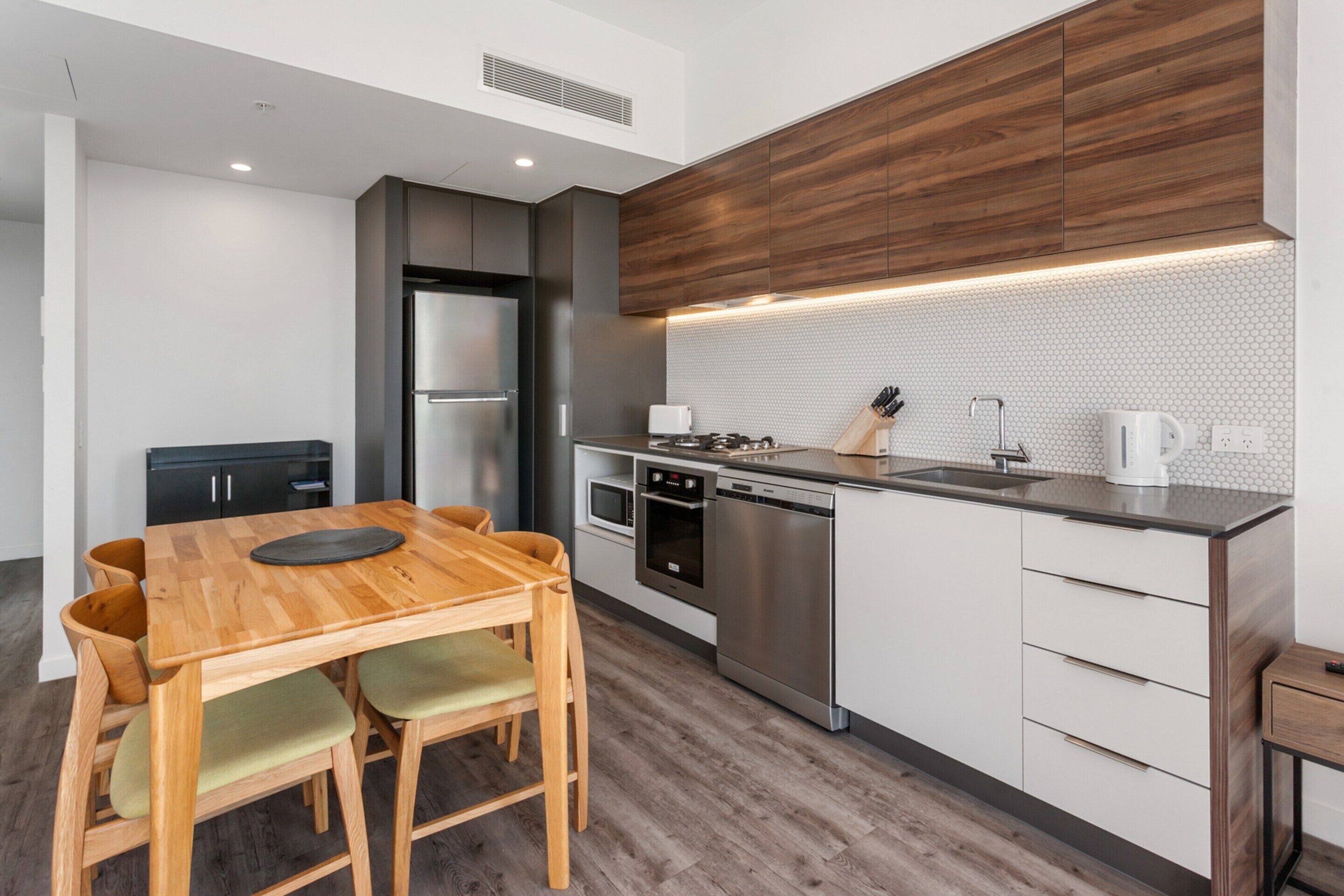 A modern kitchen with wooden cabinets, a built-in oven, and a stainless steel dishwasher.