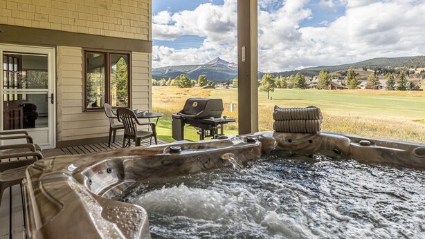 A hot tub with a view of a mountain and a grassy field. - Fairway Views | Ski Trail | Hot Tub (Big Sky)
