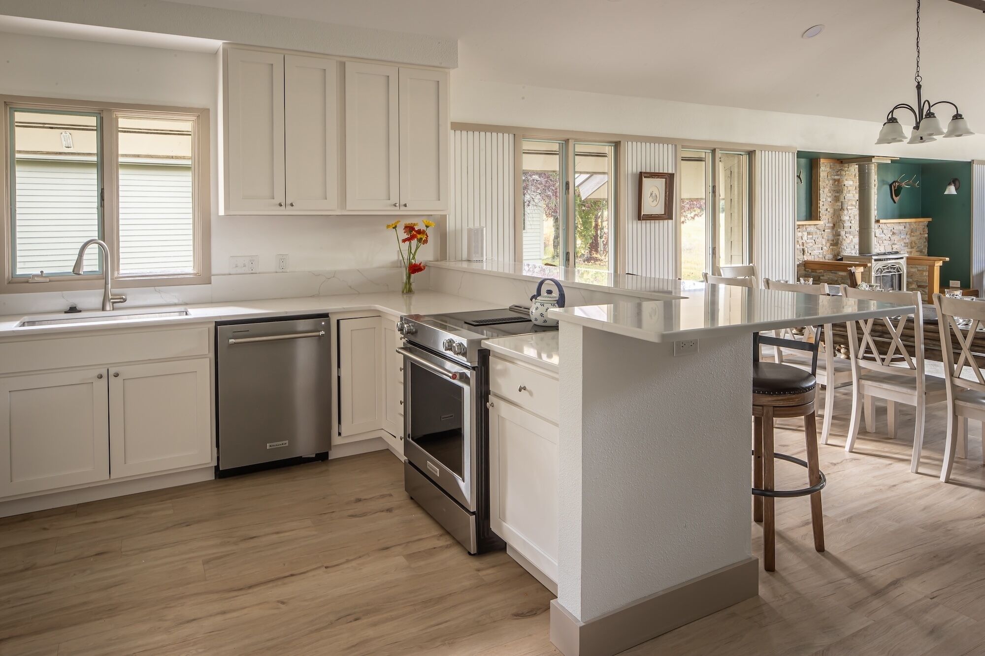 A modern kitchen with white cabinetry, stainless steel appliances, and a central island with bar stools.