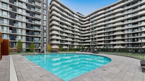 Un edifici d'apartaments modern amb piscina i zona d'estar a l'aire lliure.