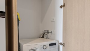 Una rentadora Bosch blanca i compacta en un petit espai de bugaderia amb una porta de fusta i parets de tons clars.