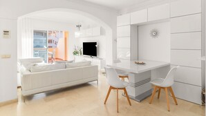 Ein modernes Wohnzimmer mit Sofa, Esstisch, Stühlen und Fernseher.