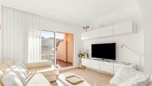 Ein modernes Wohnzimmer mit einer Couch, einem Couchtisch, einem Fernseher und einem Balkon mit Schiebetüren.