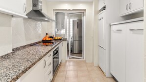 Eine moderne Küche mit weißen Schränken, Granit Arbeitsplatten, Edelstahlgeräten und einer zentralen Kochinsel mit Obst und Gemüse.