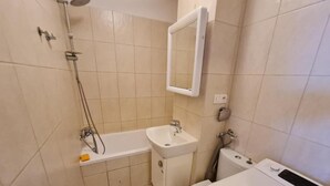 Een badkamer met een bad, wastafel, toilet en een wasmachine.