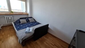 Een slaapkamer met een bed, een radiator, een raam en een houten vloer.