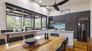 A modern kitchen with a dining area, large windows, and a ceiling fan. - Stylish 3-bedroom and Outdoor Grill and Pizza Oven (Drysdale)