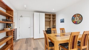 A dining area with a wooden table and chairs, a white door, and a wall clock. - Madecomfy Spacious Canberra LI (Canberra)