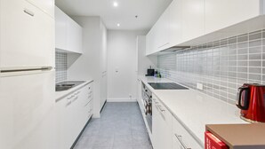 A modern kitchen with white cabinetry, a tiled backsplash, and stainless steel appliances. - Madecomfy Spacious Canberra LI (Canberra)