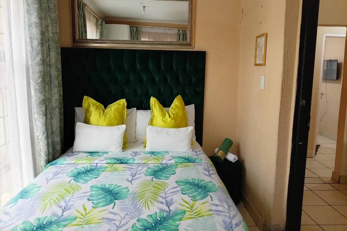 Une chambre d’hôtel avec un lit, un miroir au-dessus et une porte donnant sur une autre pièce.