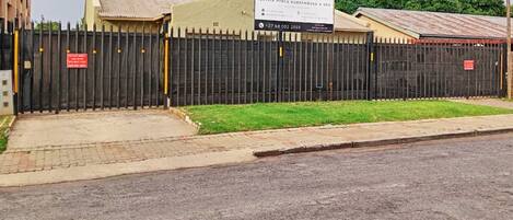 A gated property with a sign for Olivia Pines Guesthouse & Spa, a paved driveway, and a grassy area.