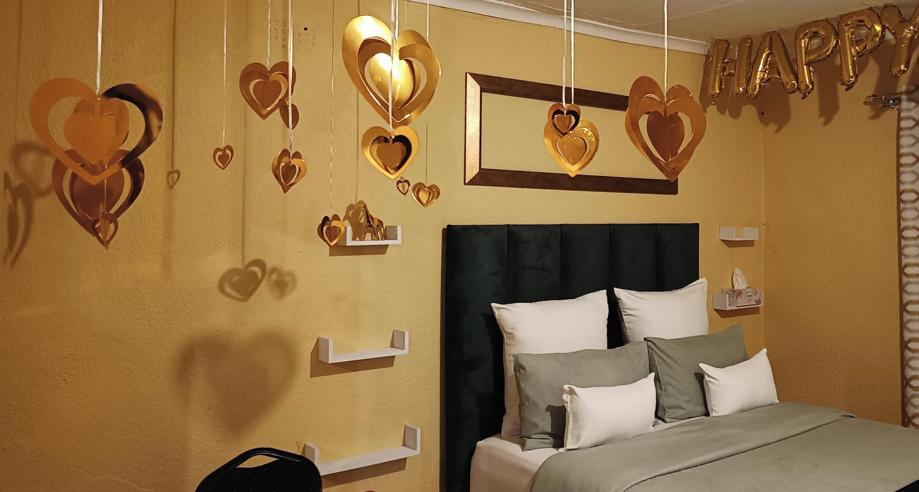 A bedroom with a bed, pillows, a headboard, and heart-shaped decorations on the wall.