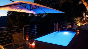 Una piscina esterna con tettoia, sdraio e un tavolo con candele.