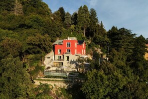 Una casa rossa con piscina e scale che conducono all'ingresso, immersa nel verde.