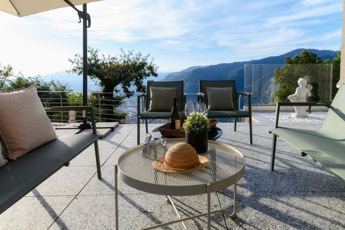 A patio with outdoor seating, a round table with a straw hat, and a bottle of wine.