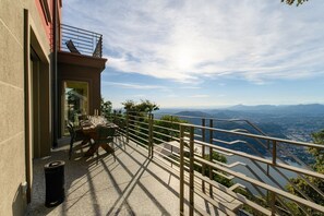 Una terrazza con tavolo apparecchiato per mangiare, ringhiera e vista sulla valle.