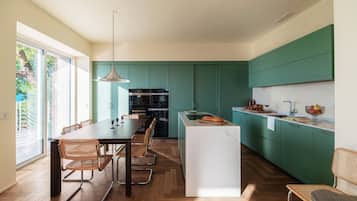 Una cucina moderna con mobili verdi, un'isola centrale e un'area pranzo con sedie.