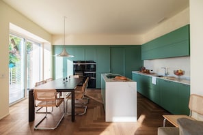 Una cucina moderna con mobili verdi, un'isola centrale e un'area pranzo con sedie.