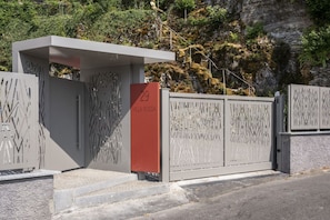 Ein modernes Gebäude mit einer nummerierten Eingangstür, einem Metallgitter und einer Treppe, die zum Eingang führt.