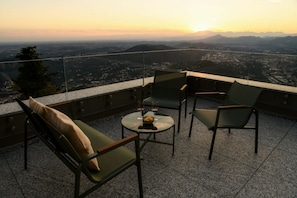 Una terrazza con vista sulla città e sulle montagne al tramonto.