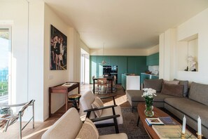 Ein modernes Wohnzimmer mit einer Couch, Sesseln, einem Couchtisch und einem Essbereich mit Tisch und Stühlen.