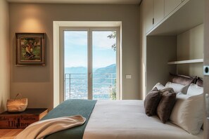 A bedroom with a bed, pillows, a framed picture, a basket, and a book.