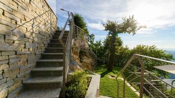 A stone staircase leading to a terrace with a view of the sea.