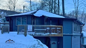 Une cabane à deux étages dotée d’un balcon, entourée d’un paysage enneigé et d’arbres.