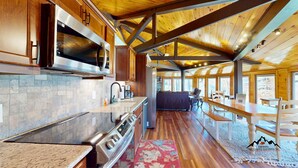 Une cuisine moderne dotée d’appareils électroménagers en acier inoxydable, d’un revêtement mural en pierre et d’un plancher en bois.