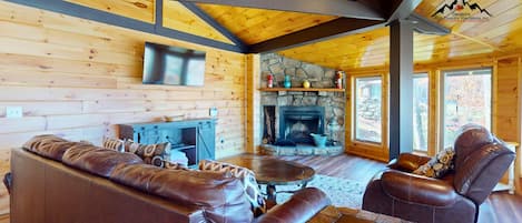 L’intérieur d’un chalet chaleureux, avec une cheminée en pierre, des meubles en cuir et des murs en bois.