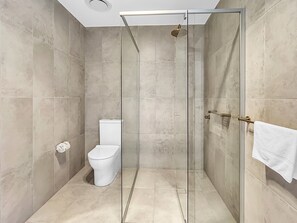 A modern bathroom with a glass-enclosed shower, a toilet, and a towel rack. - 3-bed: Riverfront Alfresco Dining & Rooftop Pool (Batemans Bay)
